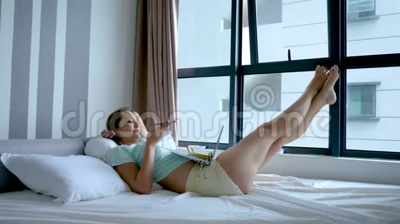 女性在家工作等待电话接听女士躺在床上肚子上放着电脑腿上放着窗户视频的预览图