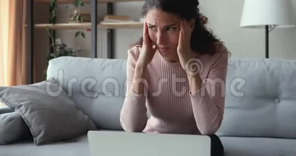担心的女人看着笔记本电脑感到沮丧读坏消息视频的预览图