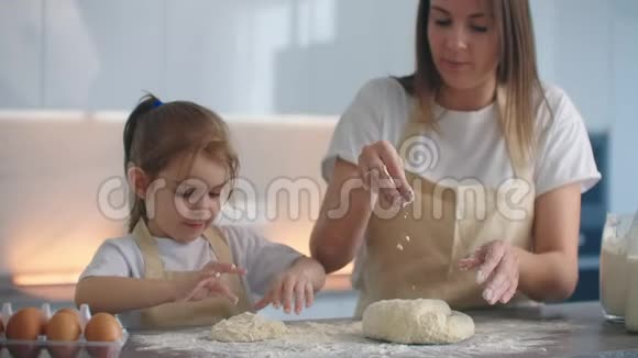 学习家庭食谱妈妈教女儿做一块空白的披萨或蛋糕用他的手用面团做成视频的预览图