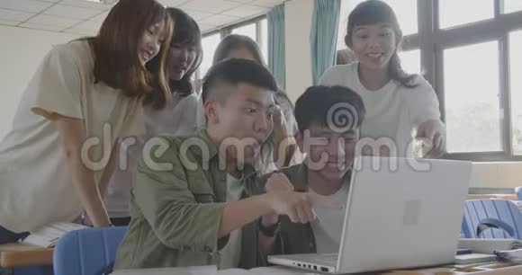 兴奋的大学生在教室里看笔记本电脑视频的预览图