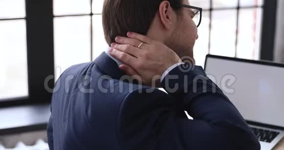 疲倦的商人在办公室里摩擦僵硬的脖子酸痛的肌肉视频的预览图