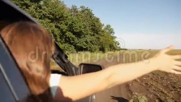 免费女性旅行者骑汽车车窗上的一只手抓住了风长发女孩坐在前面视频的预览图