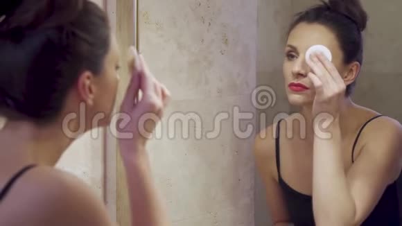 美丽的年轻女子在镜子里化妆视频的预览图