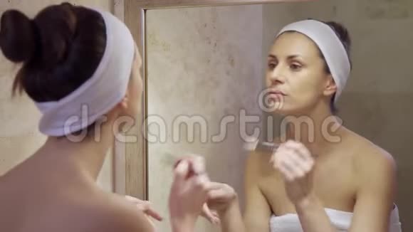 美丽的年轻女子用液体照镜子视频的预览图