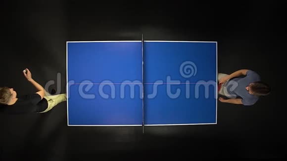 两个年轻人在黑暗的背景下玩乒乓球游戏享受竞技运动上景慢动作视频的预览图