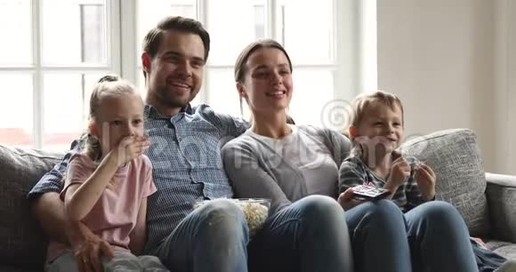 快乐的漂亮女人和丈夫和孩子一起看电视视频的预览图