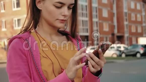体育自拍年轻漂亮的运动女孩穿着看手机一边微笑一边在手机上自拍视频的预览图