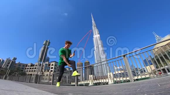 人用跳绳在迪拜的城市景观背景上跳跃慢动作视频的预览图