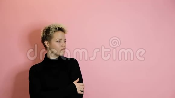 时尚满意的年轻女性右指向粉红色背景与复制空间视频的预览图