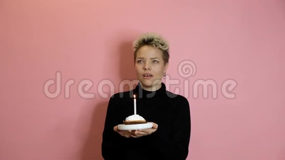 年轻时尚的女士用一块馅饼和蜡烛在粉红色背景下庆祝生日视频的预览图