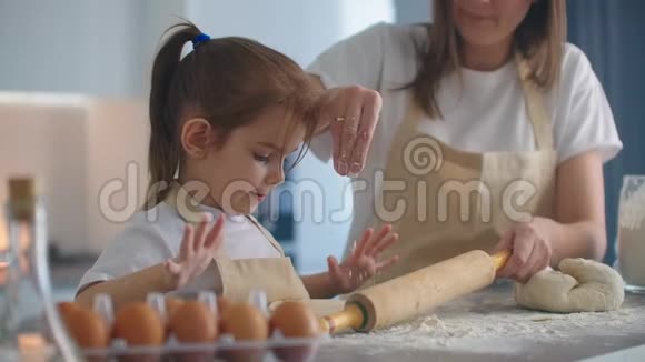 妈妈帮女儿在厨房里卷面团来烤饼干妈妈和女儿一起在厨房里烤披萨女孩视频的预览图