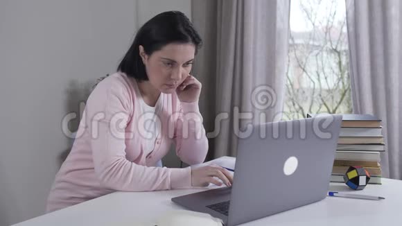 紧张的白种人年轻女人看着屏幕听到什么关闭笔记本电脑并离开Brunette妻子或母亲视频的预览图