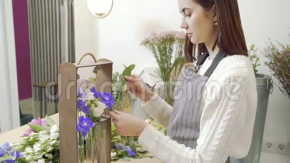女青年花店在车间或商店里布置鲜花和绿叶的礼品视频的预览图