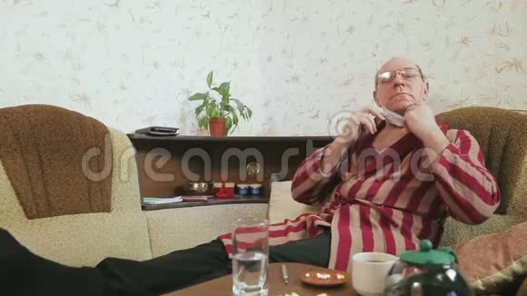 一个穿着浴袍的男人在家里的沙发上喝着浓茶视频的预览图