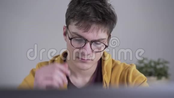 疲惫的白种人男孩的特写脸摘下眼镜擦鼻子聪明认真的大学生视频的预览图