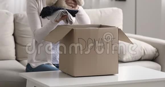 妇女在儿童捐赠箱里装衣服和玩具熊视频的预览图