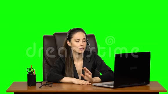 商务女性戴着耳机用网络摄像头说话带着喜悦的情绪看着笔记本电脑绿色屏幕视频的预览图