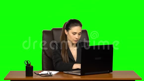 女孩热情地在笔记本电脑后面工作微笑着享受结果绿色屏幕视频的预览图