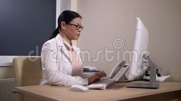 疲惫的儿科医生在诊所用电脑视频的预览图