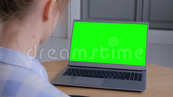 女人看着一台空绿色显示器的笔记本电脑肩上看视频的预览图