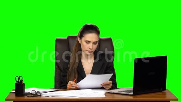 穿着紧身的女性阅读文件划掉所写的东西把皱巴巴的纸从桌子上扔掉绿色屏幕视频的预览图