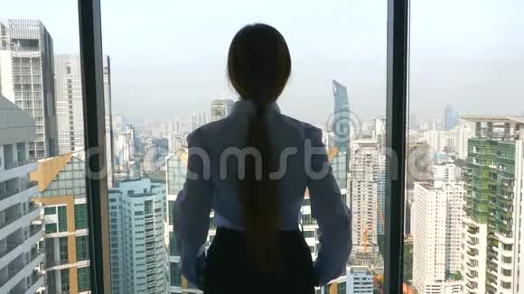 商务女性站在办公室眺望城市的窗后景色视频的预览图