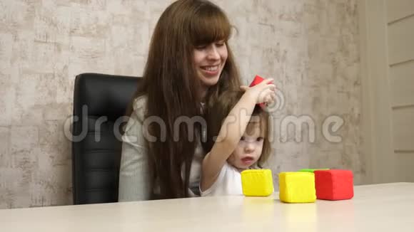 女人和一个孩子在家工作检疫冠状病毒母亲和孩子在工作时在多种颜色的立方体中玩耍视频的预览图