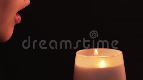 心灵感应一个女人吹灭燃烧的蜡烛孤立的黑色背景宗教信仰的概念视频的预览图