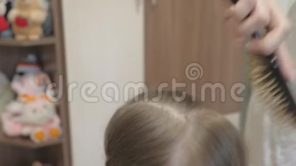 母亲用梳子梳孩子的头发特写镜头女儿美丽发型的概念一个幸福的家庭妈妈视频的预览图