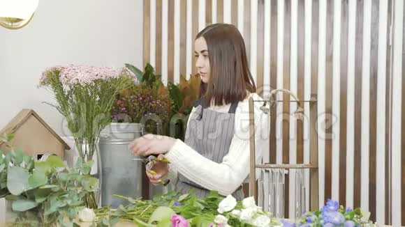 女青年花店在车间或商店里布置鲜花和绿叶的礼品视频的预览图