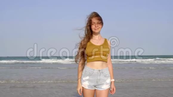 微笑美丽的女孩长发站在海滩上镜头里看视频的预览图