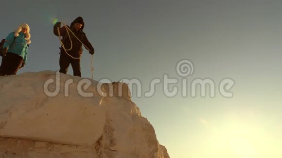 登山队员用绳子爬上一座山自由女人帮助男性旅行者爬山游客的团队合作视频的预览图