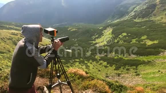 年轻摄影师用三脚架拍摄山景视频的预览图