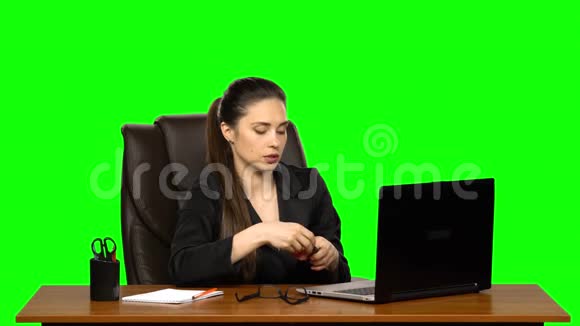 女人坐在皮椅上的桌子上睫毛上涂着睫毛膏看着绿色屏幕上的红色镜子视频的预览图