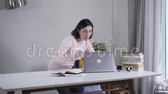 成年白种人女性打开笔记本电脑惊讶地看着屏幕的肖像年轻的黑发女人视频的预览图