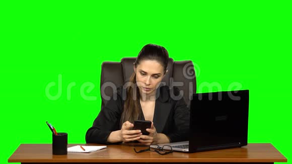 商务女性坐在办公桌前愤怒地在手机上写着一条信息绿色屏幕工作室视频的预览图