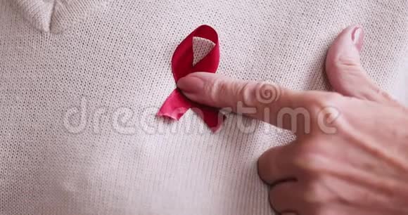 年长的成年女子手拿红丝带胸前戴着红丝带视频的预览图