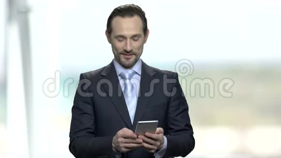 微笑的商人在他的智能手机上阅读信息视频的预览图