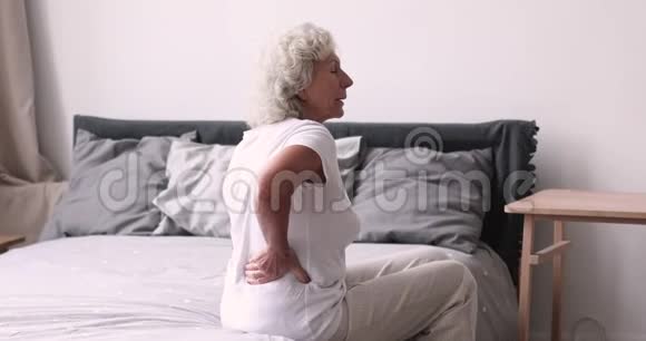 坐在床上搓背感觉背痛的老年妇女视频的预览图