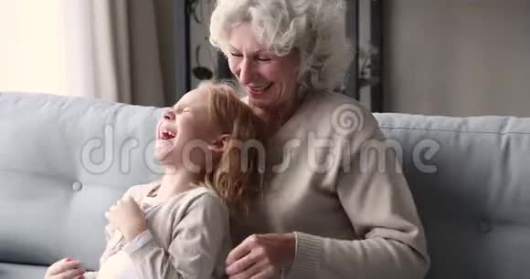 快乐的老奶奶在家挠痒痒可爱的小孙女视频的预览图