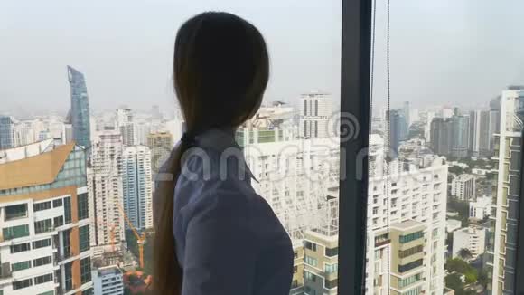 商务女性站在办公室向窗外眺望摩天大楼视频的预览图