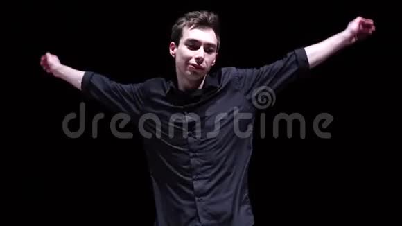 穿黑色衬衫的快乐男人在黑色背景上休息跳舞视频的预览图