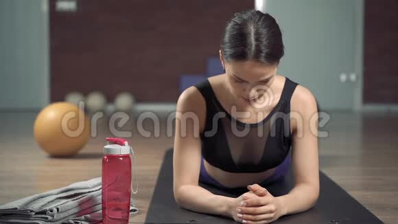 运动服装的年轻健身妇女在家或在工作室做木板运动视频的预览图
