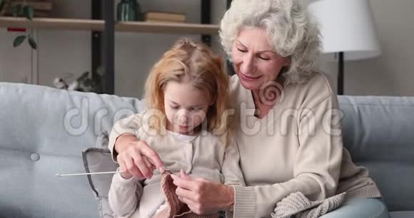 老奶奶在沙发上教可爱的孙女编织视频的预览图