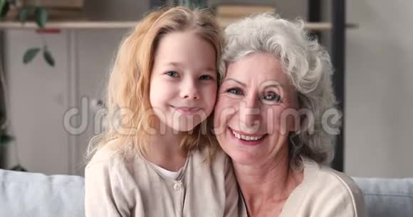 可爱的小孙女拥抱微笑的成熟奶奶画像视频的预览图