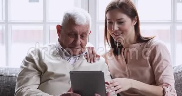成年孙女用数码平板电脑教老爷爷视频的预览图