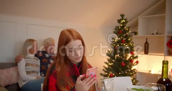 年轻的红发女孩用智能手机爷爷奶奶抱着可爱的沙发视频的预览图