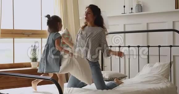 快乐的年轻妈妈和小可爱的女儿斗枕头视频的预览图