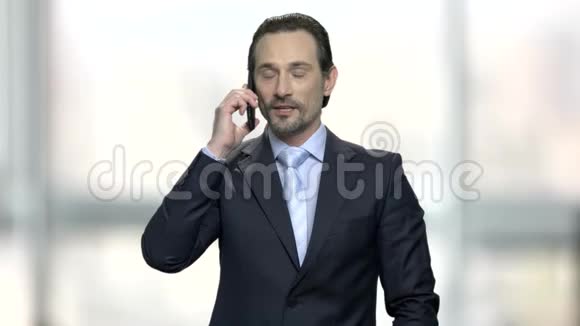 英俊的商人用手机说话视频的预览图