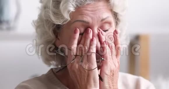 疲惫的老太太摘下眼镜感觉眼睛疲劳的概念视频的预览图